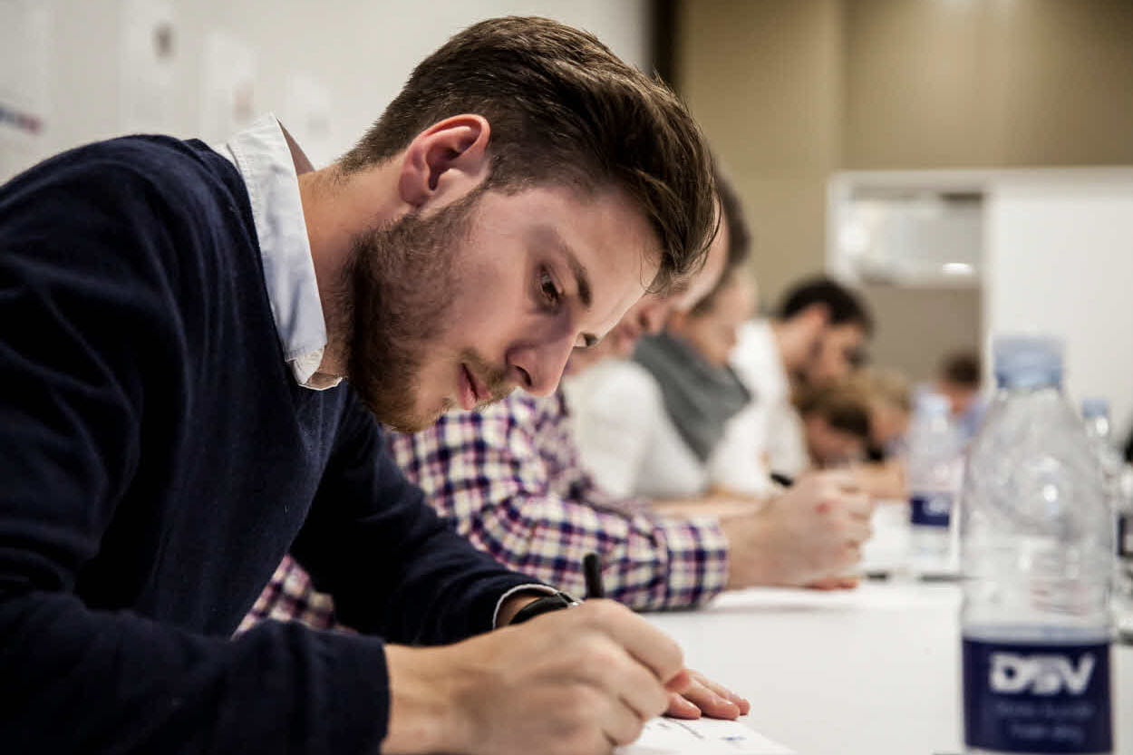 Noor meespraktikant kirjutab konverentsiruumis märkmeid